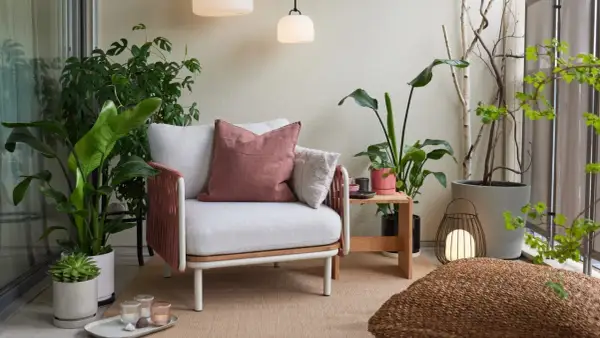 Gemütliche loggia balkon mit Sessel, Kissen, Pflanzen und Laterne.