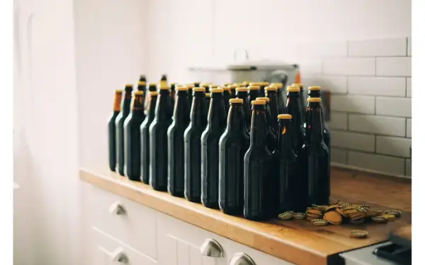 Rząd ciemnych butelek piwa, gotowych do degustacji. Zestaw brewkit Coopers czeka na otwarcie.
