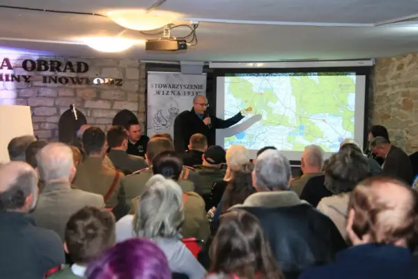 Prezentacja o Hubalu i jego szlaku bojowym. Mężczyzna wskazuje na mapę, a publiczność słucha.