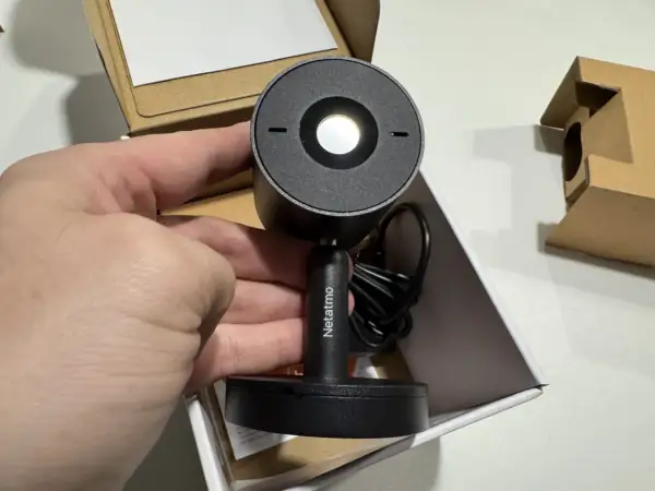 Main tenant de la nouvelle installation camera Netatmo. Le produit est dans sa boîte, prêt à être mis en place.