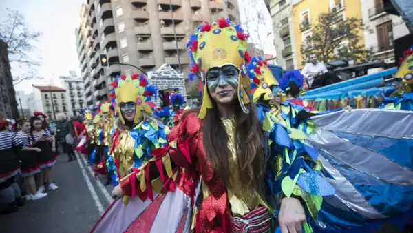 Gente disfrazada con trajes coloridos y elaborados desfila en los carnavales de Zaragoza, celebrando con alegría y arte.