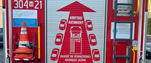 Grafika na drzwiach wozu strażackiego przedstawia korytarz życia, symbolizujący drogę dla pojazdów ratunkowych.