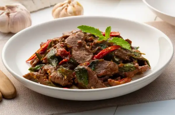 Aromatyczne wołowina po chińsku z bazylią i papryczką chili, podana w białej misce.
