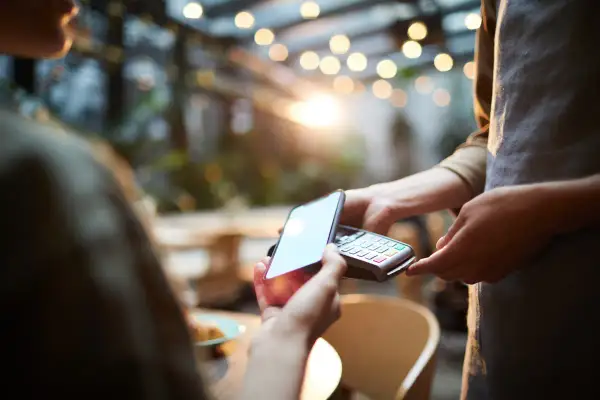 Klient płaci kartą z telefonu zbliżeniowo przy terminalu. Szybko i wygodnie.