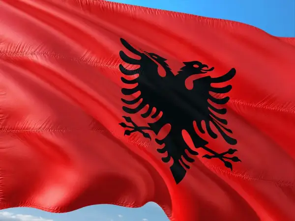 Czerwona flaga Albanii z czarnym dwugłowym orłem. W Albanii obowiązuje waluta lek.