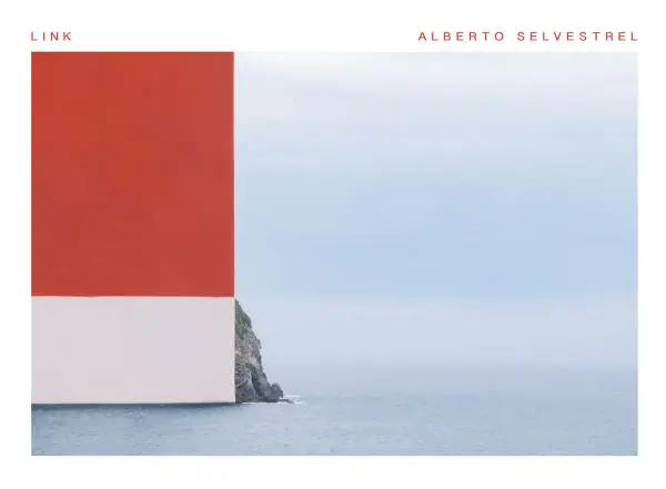 Scogliera rocciosa con mare calmo e cielo azzurro, con un blocco rosso e bianco che incombe a sinistra. Opera di Alberto Selvestrel.
