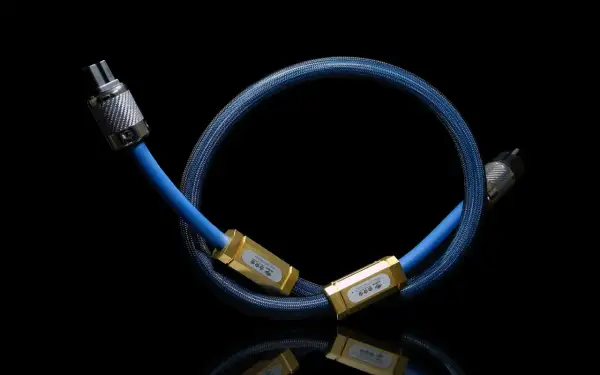Błękitny kabel z plecionką, zakończony złotymi elementami z logo korony. To Siltech Triple Crown, symbol doskonałości dźwięku.