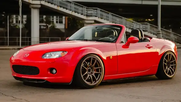 Mazda MX-5 rouge rutilante, parfaite pour un jeune permis rêvant de sa première voiture sport.