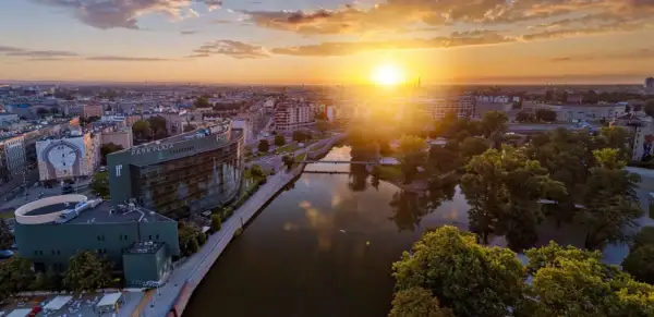Zachód słońca nad Odrą we Wrocławiu, idealny na city break. Widok na Park Plaza i malownicze kamienice.