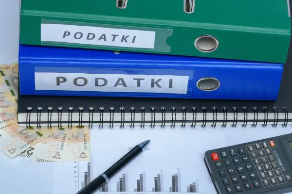 Segregator z napisem "PODATKI", pieniądze, kalkulator i wykres. Szukasz sposobu, jak zmniejszyć podatek za budynki gospodarcze?