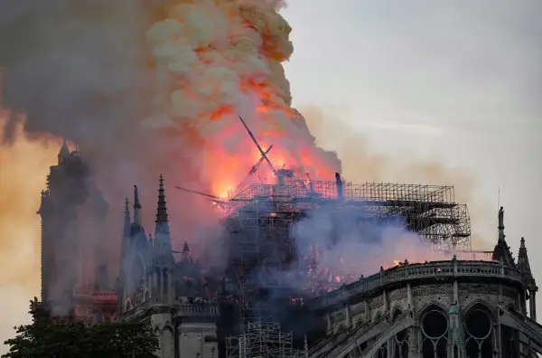 Notre Dame pożar: płomienie trawią dach katedry, unoszą się kłęby dymu. Widoczne rusztowania i zniszczona konstrukcja.