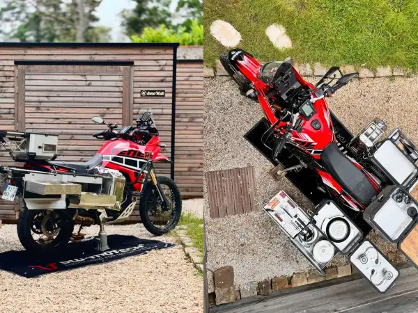 Una moto trail roja lista para la aventura, con maletas y equipo de camping.