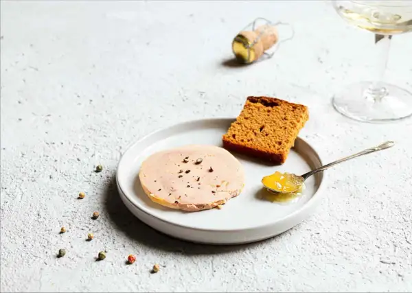 Tranche de foie gras sur assiette avec pain d'épices et confiture. La question "foie gras à partir de quel âge" reste ouverte.