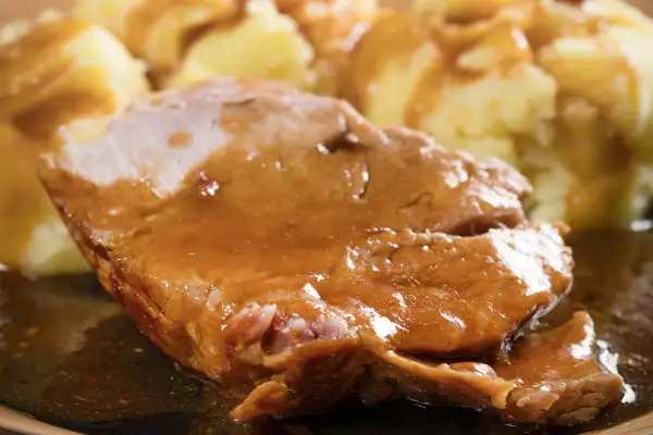 Mięciutka karkówka w sosie, podana z purée ziemniaczanym. Danie wygląda apetycznie i sycąco.