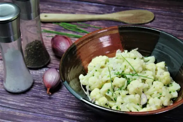 Leckerer gekochter blumenkohlsalat rezepte mit Schalotten und Schnittlauch. Daneben Salz- und Pfefferstreuer.