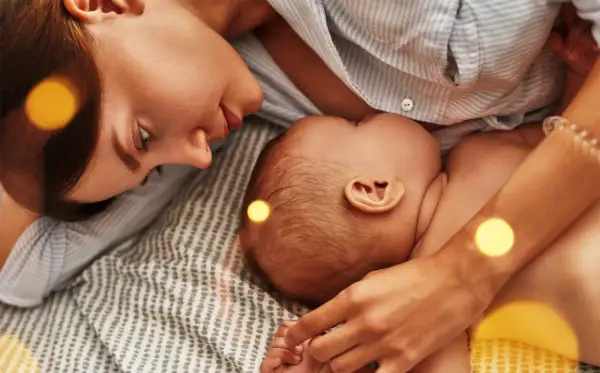 Mama czule patrzy na dziecko, które karmi piersią. Czasem pojawia się kryzys laktacyjny w 4 miesiącu, ale miłość i bliskość pomagają go pokonać.