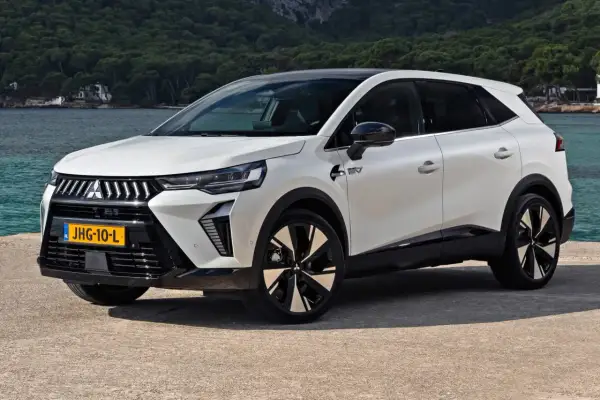 Nowy model Mitsubishi, biały SUV z czarnym dachem, stoi nad wodą. Nowoczesne linie i felgi podkreślają jego dynamiczny charakter.