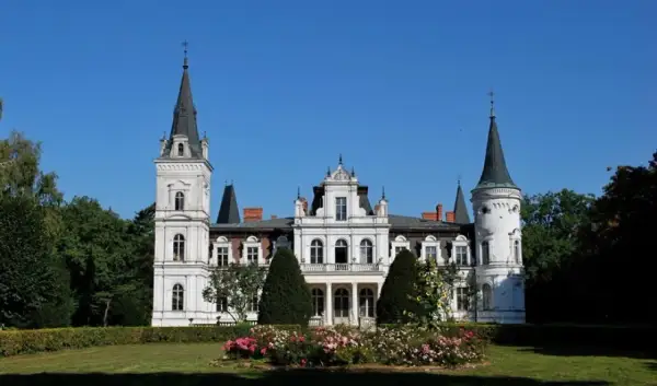 Imponujący pałac w Posadowie z wieżami i ozdobnym ogrodem.