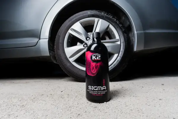Butelka preparatu K2 Sigma Pro do pielęgnacji opon, stojąca obok koła samochodu. Płyn pomoże Ci zadbać o to, jak przechowywać opony, by służyły dłużej.