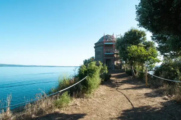 Sentiero panoramico verso un edificio storico sull'isola Bisentina. La visita è un'esperienza suggestiva tra natura e storia.