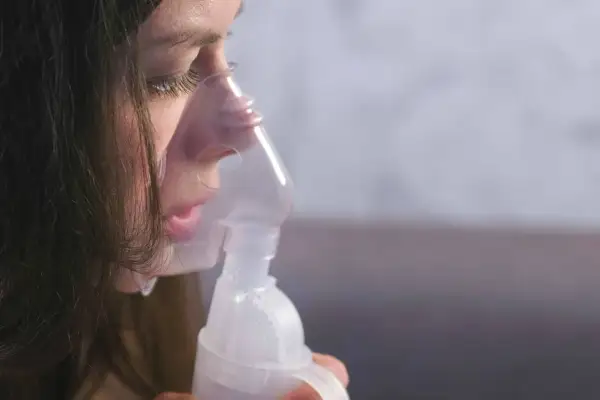 Dziewczynka z maską inhalatora na twarzy, która pomaga jej w walce z anoro.