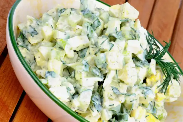 Kartoffelsalat mit Joghurt, Eiern und Gurken, garniert mit Dill. Ein leichter und erfrischender Salat.
