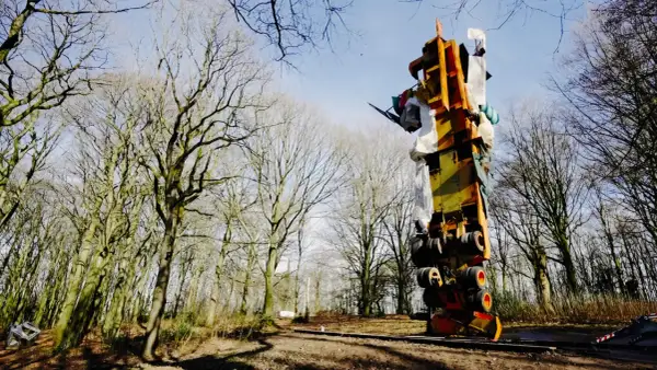 Im tony cragg skulpturenpark ragt eine bunte, auf dem Kopf stehende Konstruktion aus Metall und Stoff in den Himmel, umgeben von kahlen Bäumen.
