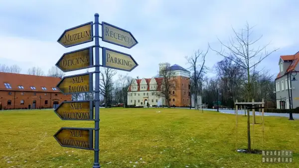 Zamek Topacz: drogowskaz wskazuje drogę do muzeum, oficyny, sali balowej, kolumnowej i kominkowej. Atrakcje czekają!