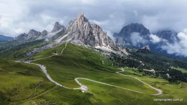 Kręta droga na Passo Giau w Dolomitach, otoczona zielonymi wzgórzami i skalistymi szczytami.