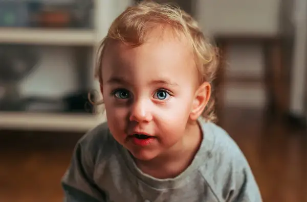 Niebieskie, uciekające oko dziecka z blond lokami, patrzy z zaciekawieniem.