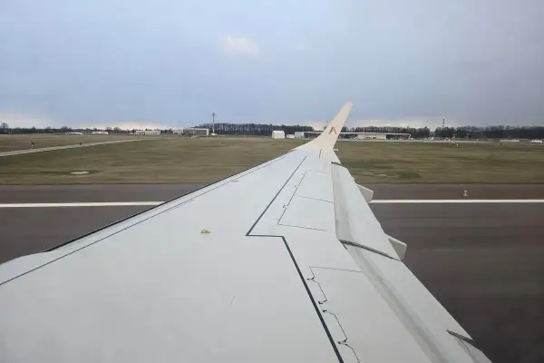 Skrzydło samolotu na pasie startowym. W tle lotnisko, przygotowania do lotów Lublin Rzym.