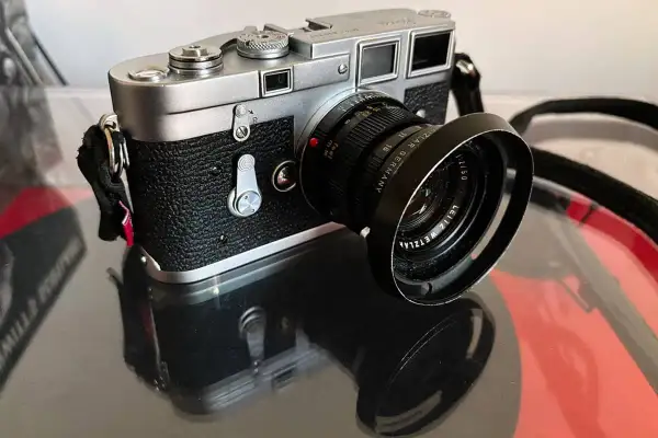 A classic Leica M3 camera with a Leitz Wetzlar lens sits on a reflective surface, ready to capture timeless moments.