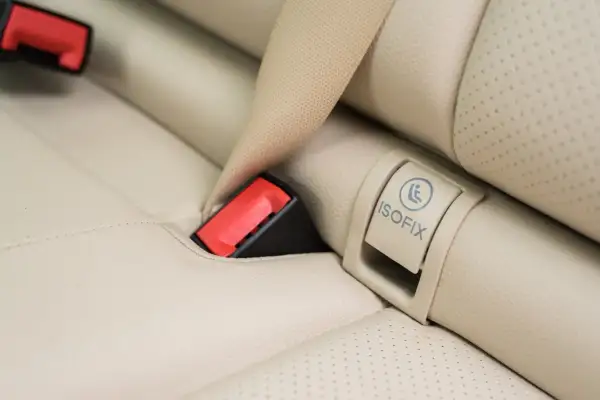 Widoczny symbol ISOFIX na jasnej tapicerce fotela samochodowego to klucz do bezpiecznego montażu fotelika.