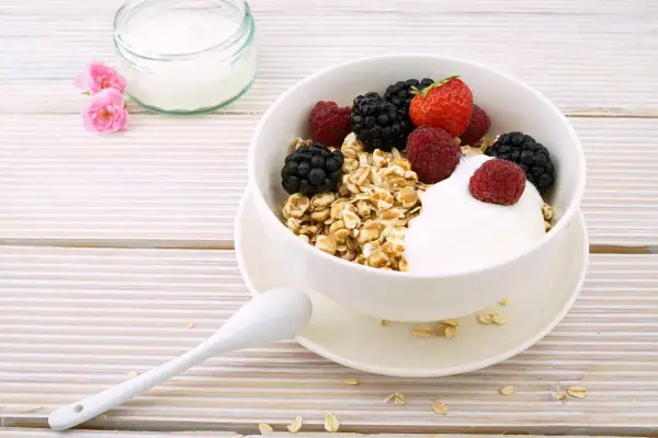 Un delizioso yogurt a colazione con muesli e frutti di bosco freschi, pronto per iniziare la giornata con energia e gusto.