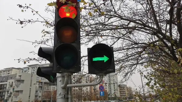 Sygnalizacja świetlna z czerwonym światłem na górze i zieloną strzałką w prawo.