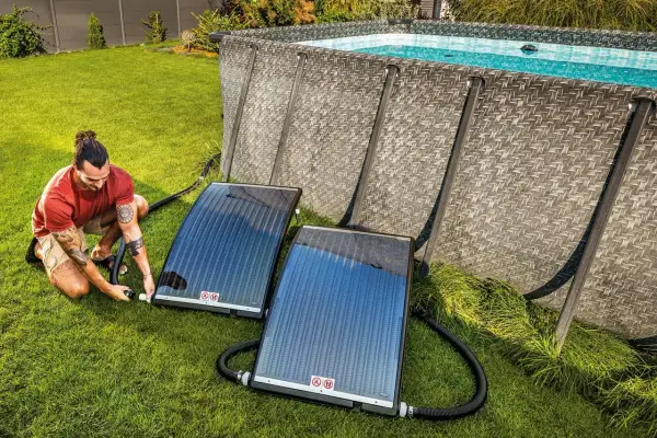 Mann schließt Solarmatten an, um den Pool zu heizen.