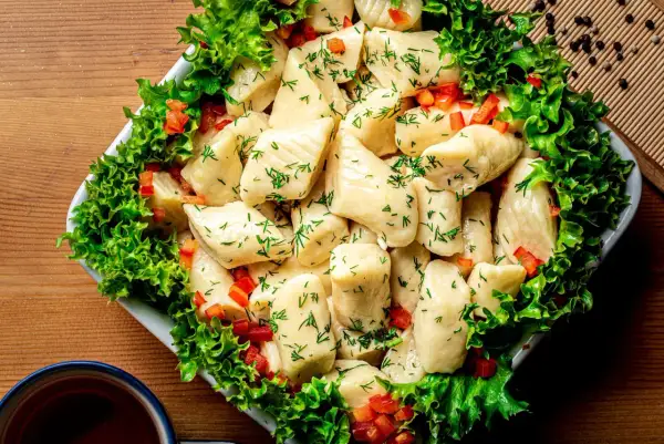 Pyszne pierogi ze szpinakiem, posypane koperkiem i papryką, otoczone sałatą. Idealne na obiad!