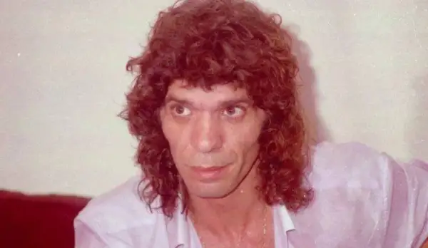 Primer plano de un hombre con cabello rizado y camisa rosa. Se especula a qué edad murió Camarón.