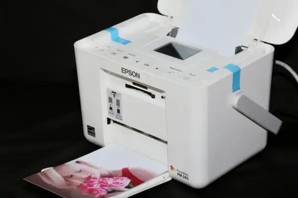 Biała drukarka Epson PictureMate PM 245 drukuje zdjęcie kobiety z różami. Szukasz, jaka drukarka najtańsza w eksploatacji?