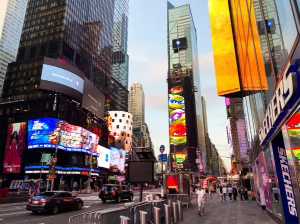 Manhattan, Nowy Jork, rozświetlony neonami i billboardami, z Żółwiami Ninja na jednym z budynków.