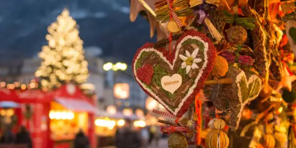 Corazón decorado con "Welcome" en un mercadillo navideño de Calatayud. Luces de árbol y puestos de feria al fondo.