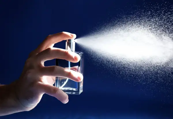 Dłoń rozpyla perfumy z buteleczki. Zastanawiasz się, na ile starcza 100ml perfum? To zależy od częstotliwości używania.
