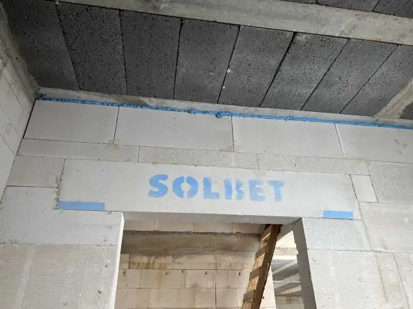 Dylatacja co to? Widoczna szczelina wypełniona pianką montażową między betonowymi stropami a ścianą z bloczków gazobetonowych.