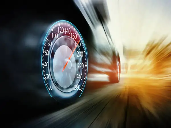 Prędkościomierz pokazuje ponad 180 km/h. Samochód pędzi drogą ekspresową, rozmazując krajobraz.