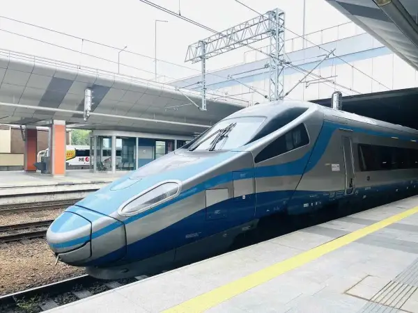 Moderner Zug mit blauen und silbernen Streifen steht am Bahnsteig. Vielleicht der Nachtzug nach Danzig?