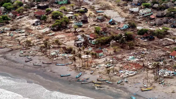 En by ödelagd av tsunamin 2004. Hus är raserade, båtar ligger utspridda på stranden. Bilden ger en känsla av förödelsen och väcker frågan: hur många dog i tsunamin 2004?