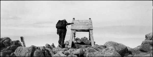 A lone hiker reaches the summit of Katahdin, a testament to perseverance in this striking fine art photography.