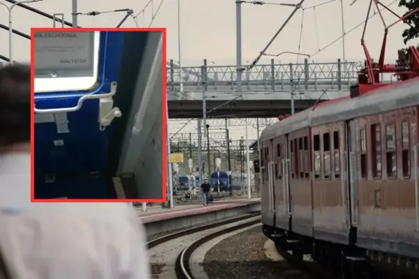 Zbliżenie na mechanizm drzwi pociągu, pokazujący, jak otworzyć drzwi w pociągu, z widokiem na peron i tory.