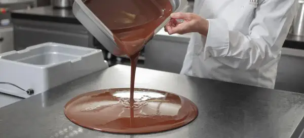 Un chef verse du chocolat fondu. Mycryo, c'est quoi ? C'est la magie du chocolat qui prend forme.