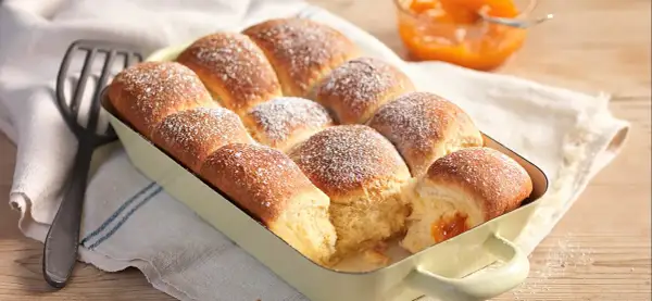 Frisch gebackene Buchteln, bestäubt mit Puderzucker, warten darauf, mit Marillenmarmelade gefüllt zu werden. Ein echtes Buchteln original Rezept.